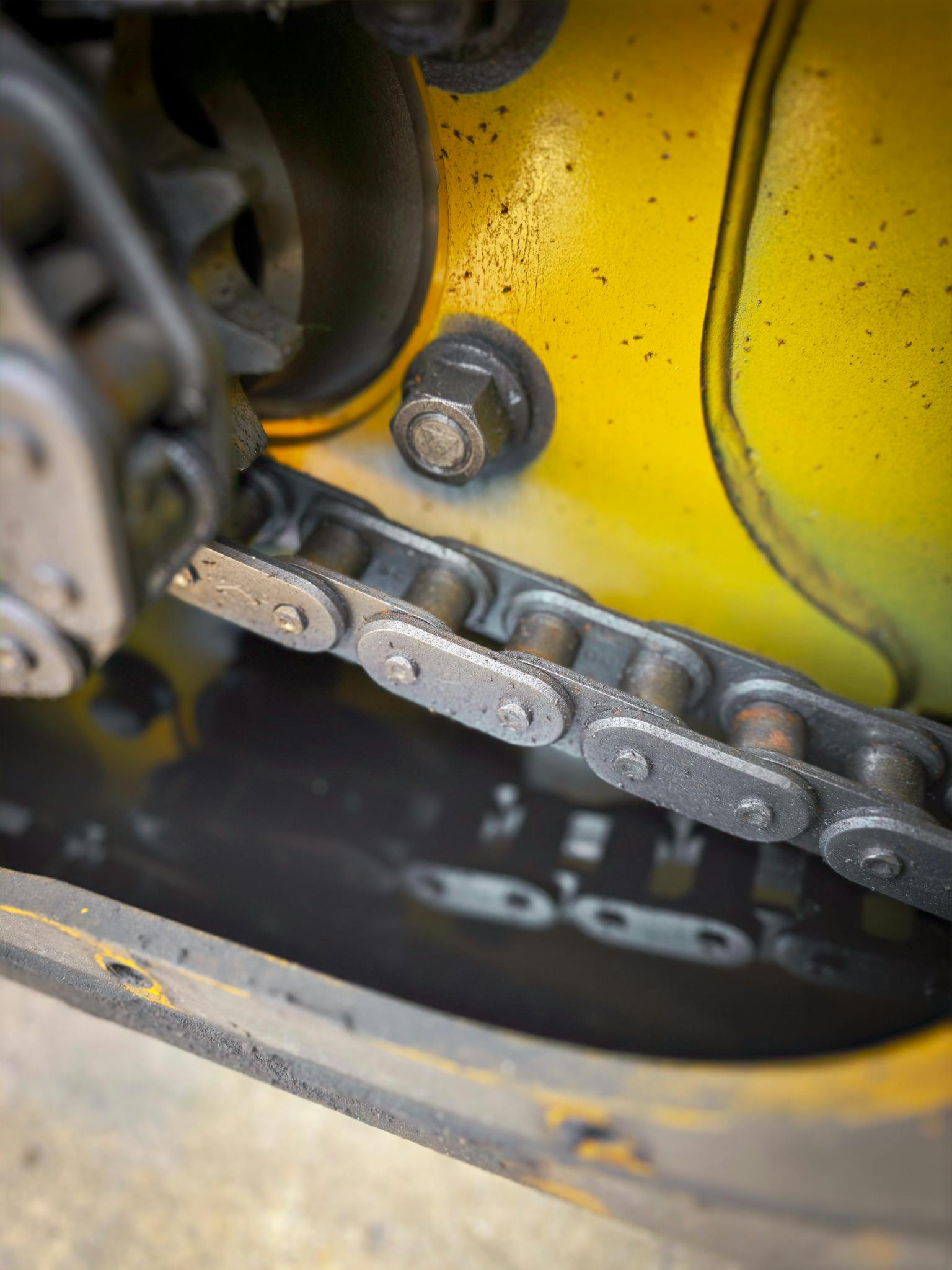 Detailed view of a machinery chain and gears with reflections and oil.